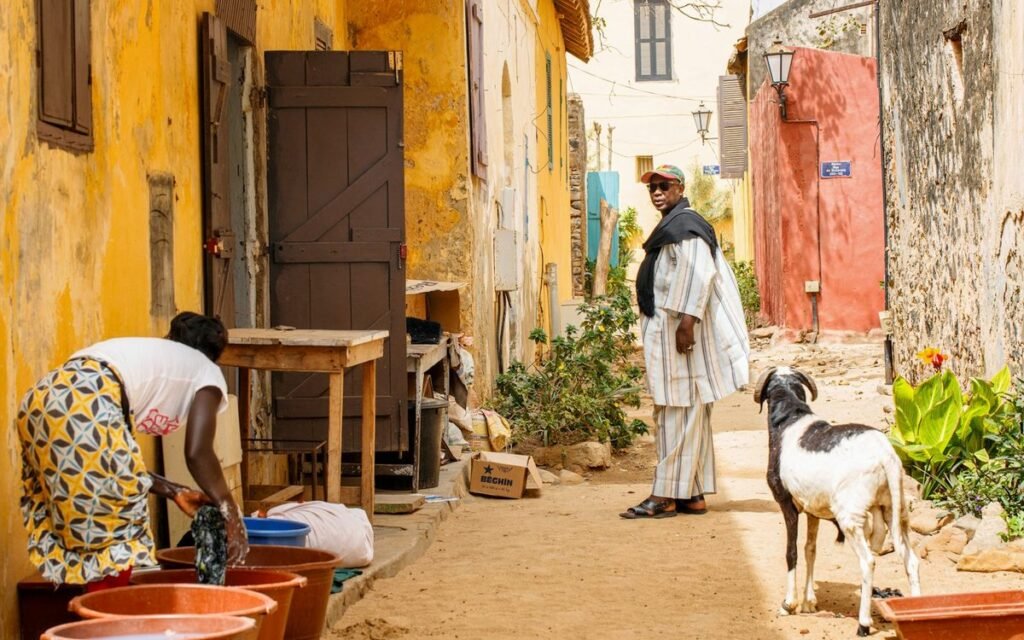 Femme en robe blanche dans une rue colorée de Saint-Louis